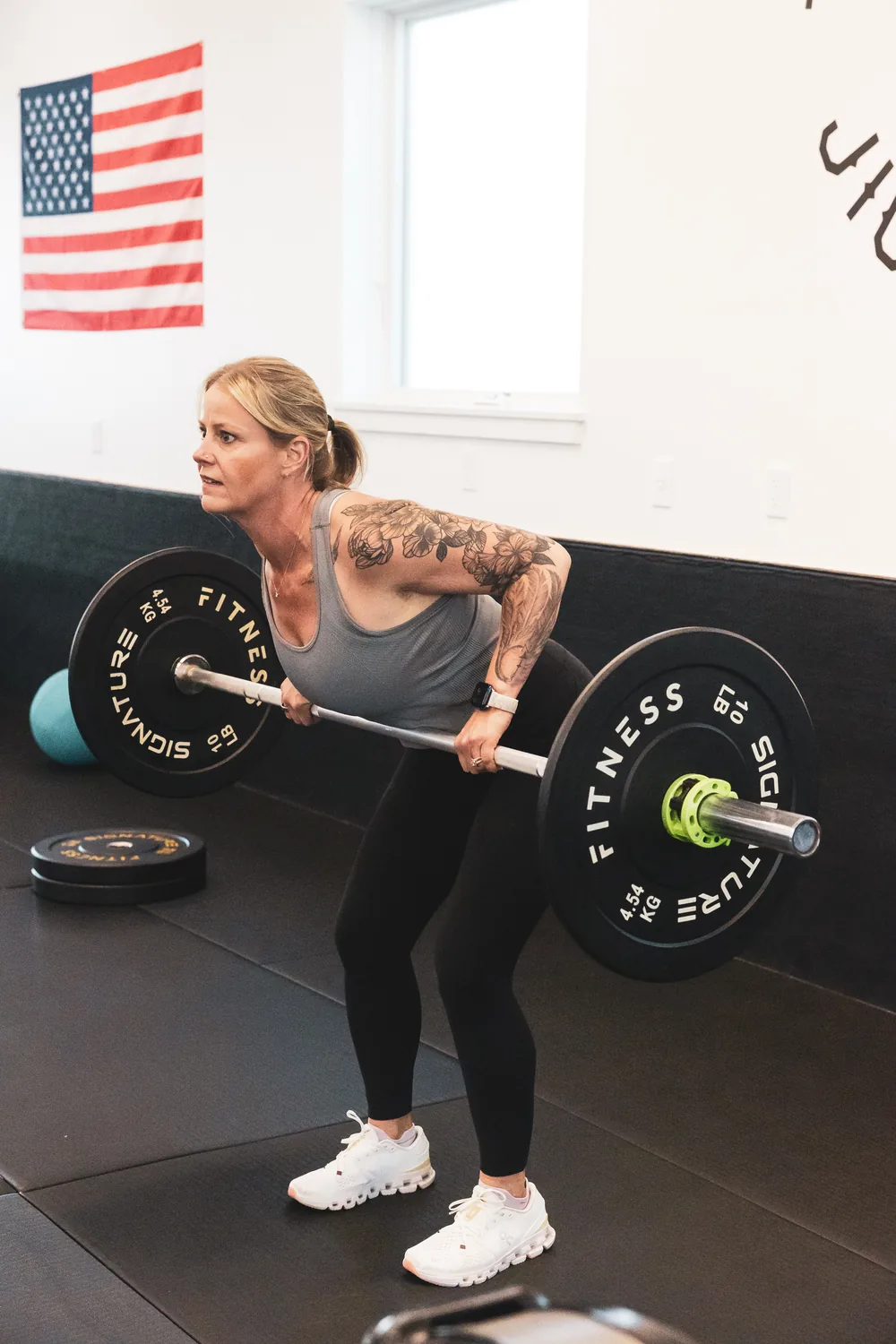 Coach Sandy Martz mid barbell curl in the gym