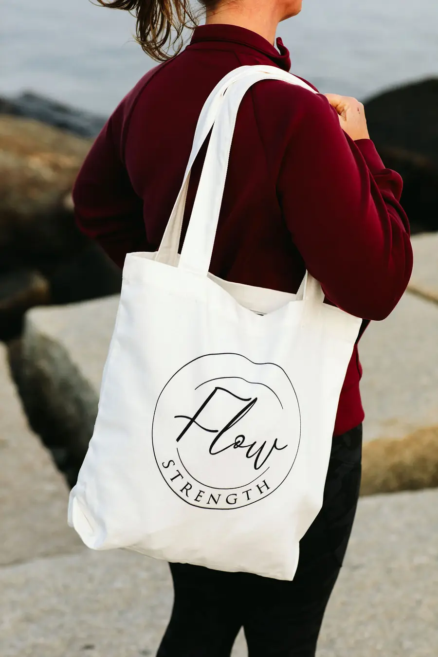 Sandy Martz on the Maine coast carrying a Flow Strength tote bag