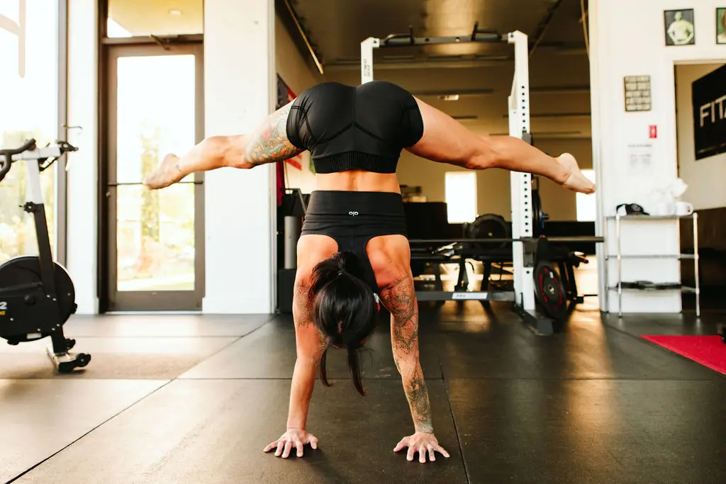 a member holding a straddle handstand on the gym floor