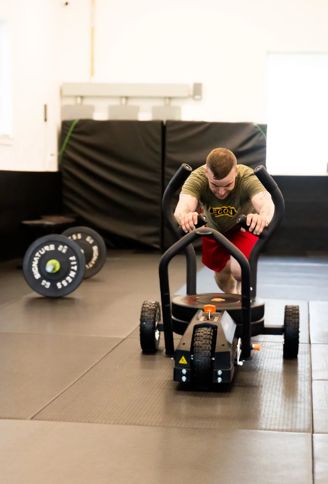 a member driving a weighted sled across the gym floor