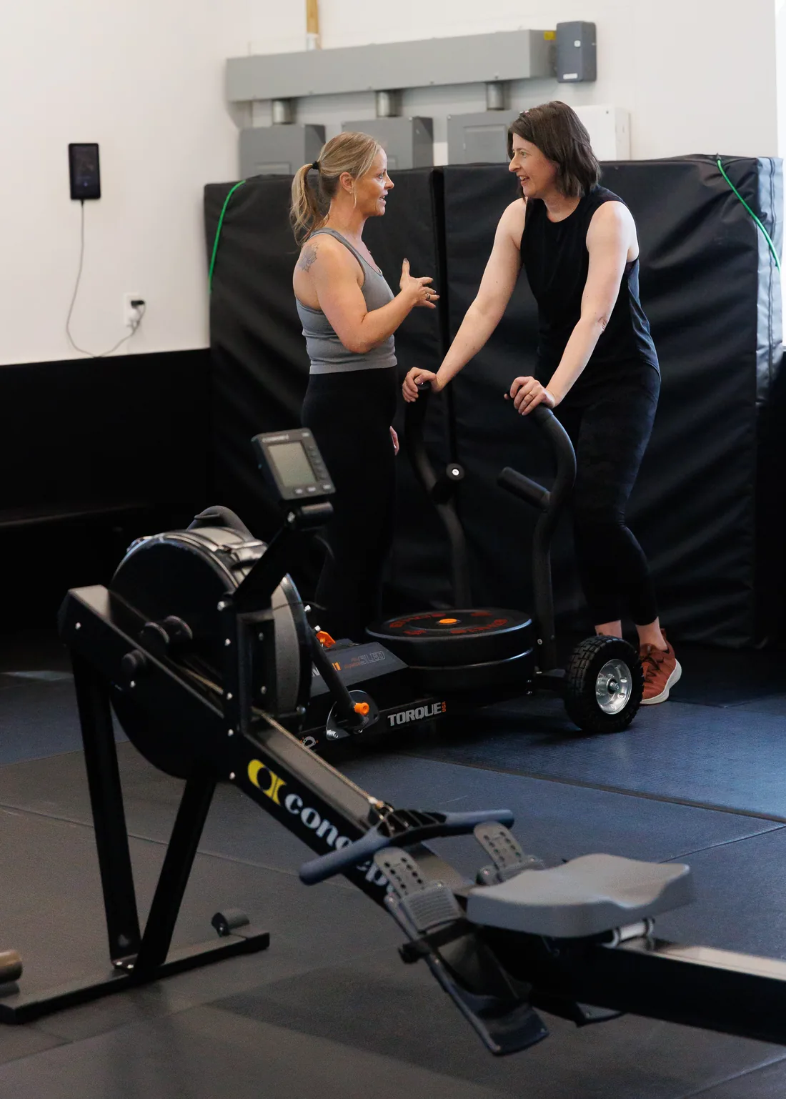 Coach Sandy in a one-to-one conversation with a client beside a rower