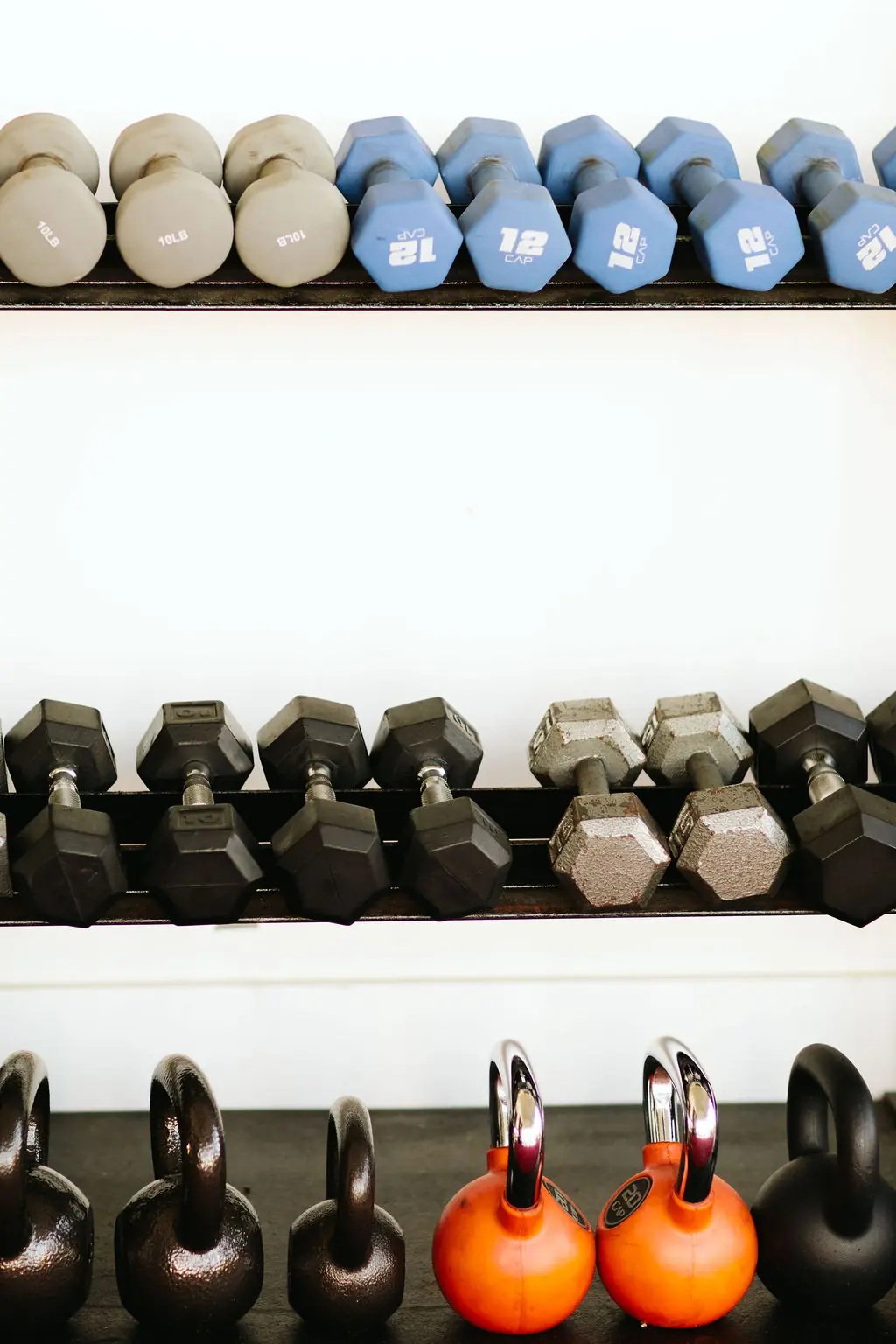 dumbbells and kettlebells racked along the studio wall