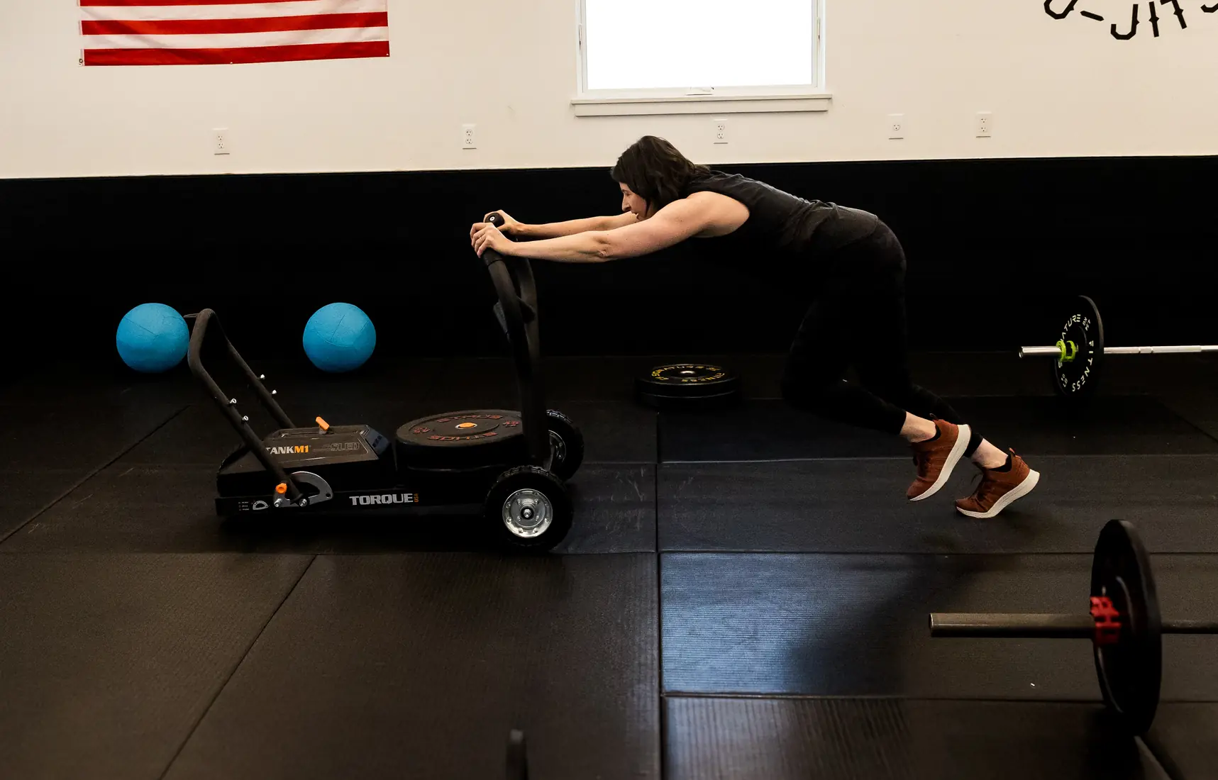 a member driving a weighted sled across the gym floor